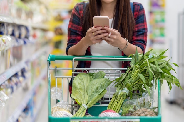 チェック製品にスマート携帯電話を使用してクローズアップ若いアジアの女性