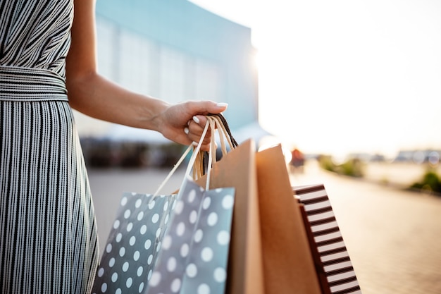 Photo closeup of young attractive woman holding a few shopping bags with newly purchased goods and clothes.