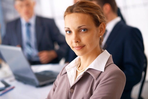 Closeup of a young businesswoman with her colleagues at the background.