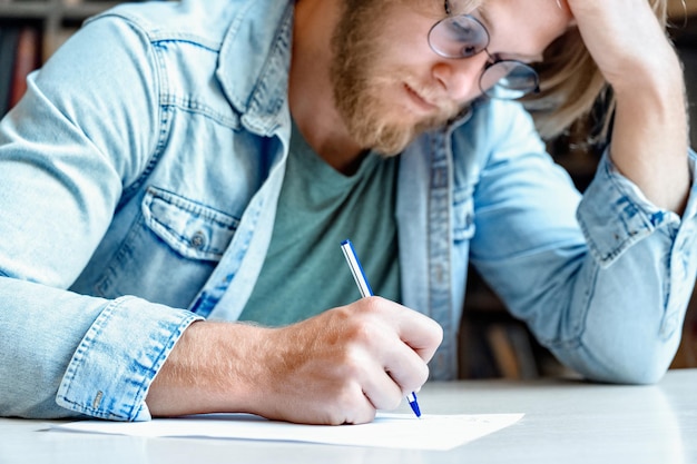 クローズアップ若い集中学生ライターは頭の手書きテストを保持します