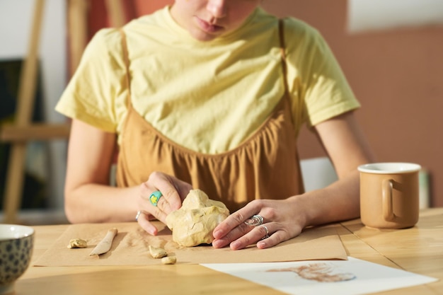 Photo closeup of young creative craftswoman making human face out of clay