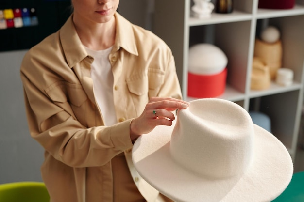 Closeup of young creative woman in casualwear holding white hat