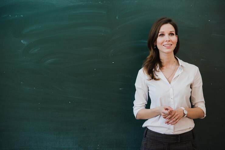 Closeup of young female teacher against chalkboard in class