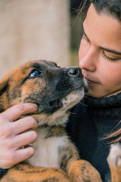 Closeup of a young female veterinarian being affectionate with a dog puppy in her arms