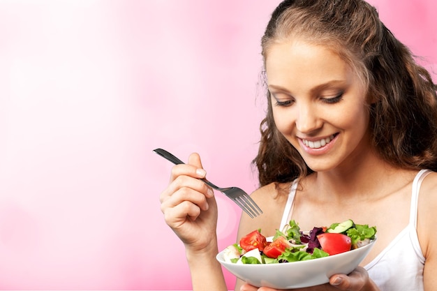 Closeup of young happy woman eating salad