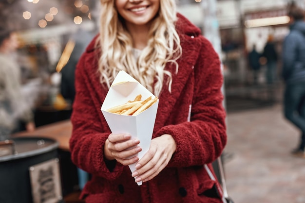 フライドポテトパッケージと若い幸せな女性のクローズアップ