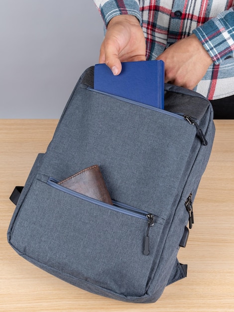 Closeup of a young male student taking out a booknotebook from a backpack