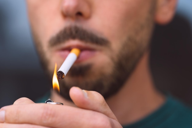 Closeup of young man lighting cigarette with lighter Smoking cigarette and nicotine addiction