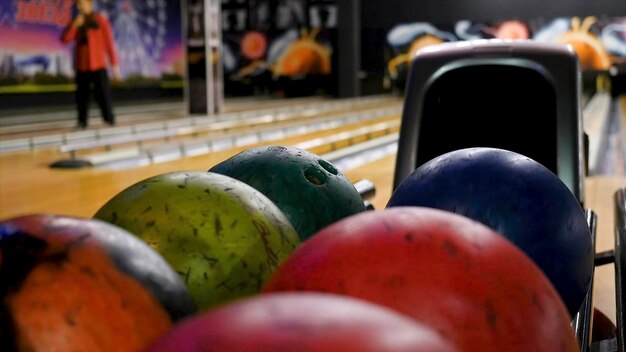 Photo closeup of young man taking bowling balls from the rack media competitive cheerful friends playing