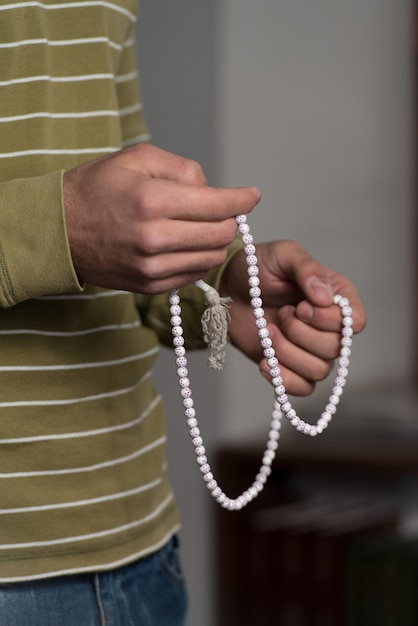 Photo closeup of young muslim man with rosary praying in mosque
