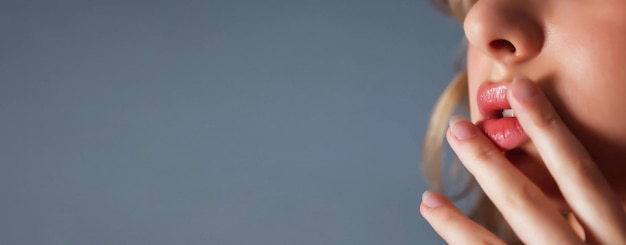 Closeup young pretty blonde woman with finger at lips flirts look against dark blue insulation background