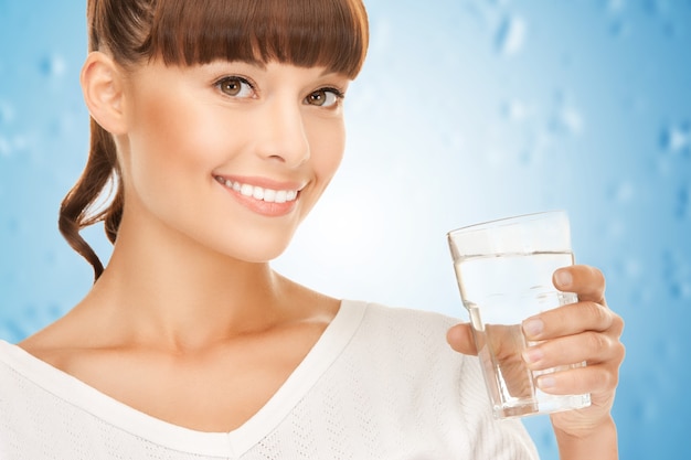 Primo piano di una giovane donna sorridente con un bicchiere d'acqua