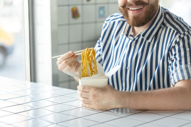 Closeup of a young unidentified mans hand in a shirt are holding wooden sticks chinese noodle