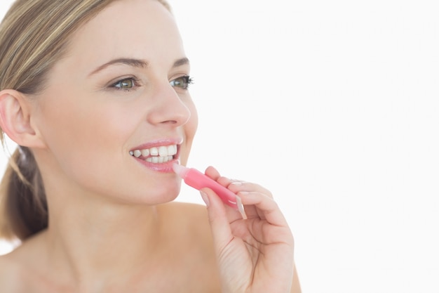 Closeup of young woman applying lipgloss