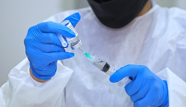 Closeup young woman doctor hands who use syringe draw vaccine from vial