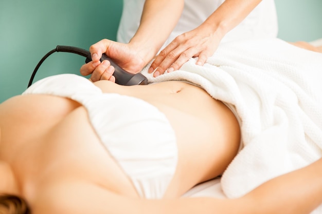 Closeup of a young woman getting a reductive belly session at a health and beauty clinic and spa