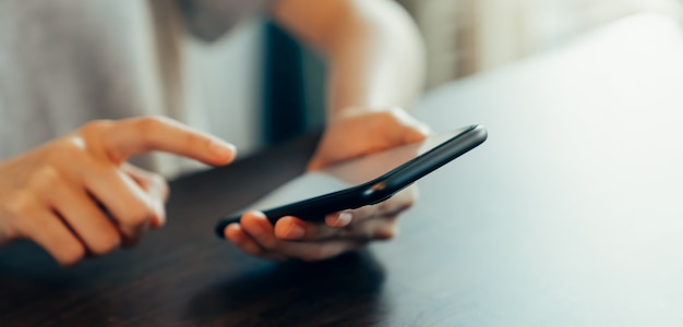 Closeup of young woman hand holding smartphone and chatting with friends at social network.