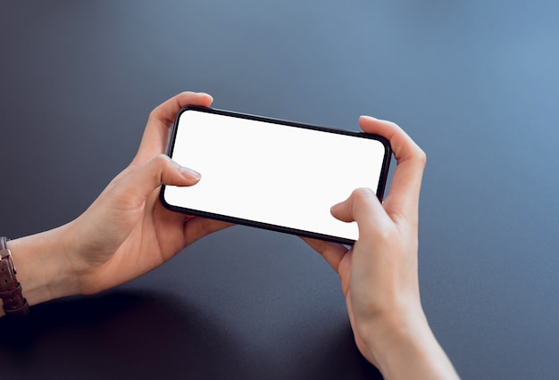 Closeup of young woman hand holding smartphone on the table and the screen is blank	