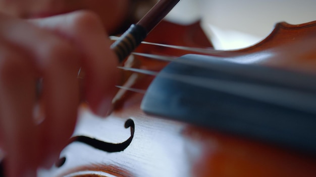 Closeup young woman hand playing violin Teenage girl using bow Female violinist practicing music