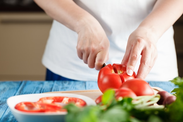 Крупным планом молодой женщины в кухне нарезка овощей