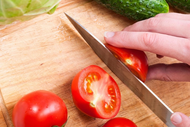 Closeup Of Young Woman In Kitchen Cutting Vegetables