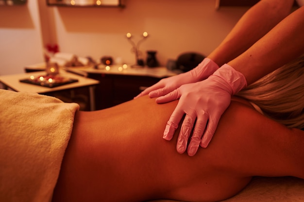 Closeup of young woman relaxing during a body massage in spa salon