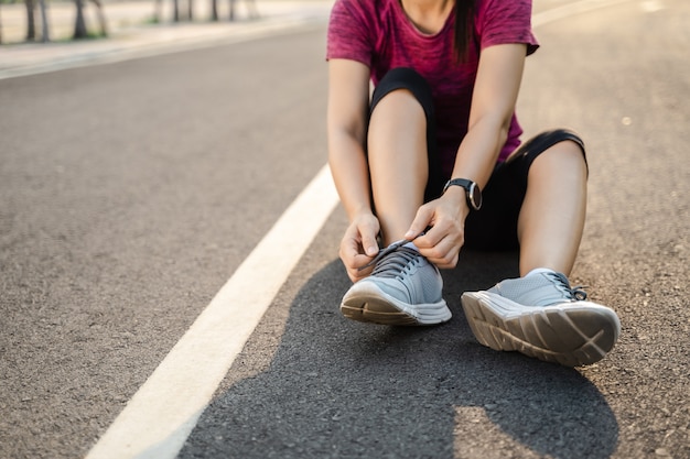 Primo piano del corridore della giovane donna che lega i suoi laccetti. concetto di salute e fitness.