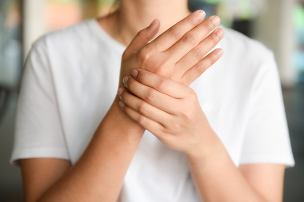 Closeup young woman sitting on sofa holds her wrist. hand injury and feeling pain. 