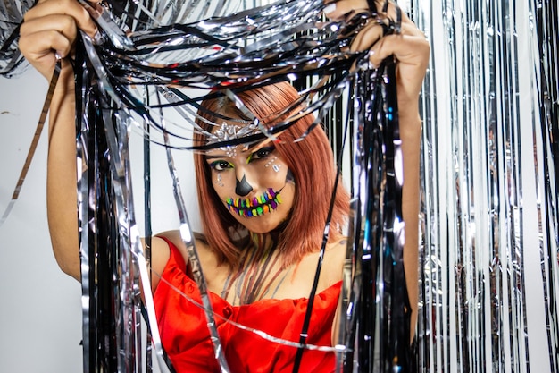 Photo closeup of young woman with makeup for halloween hidden among shiny silver and black strips