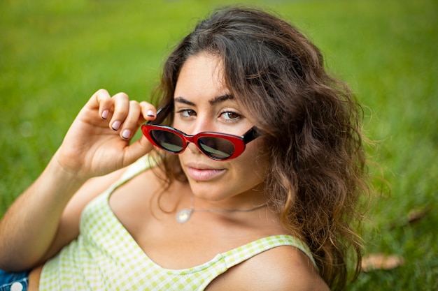 Closeup of young woman with sunglasses on the grass