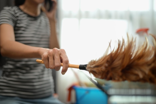 Foto closeup young woman woman dusting shelf cleaning her house chores and hygiene concept