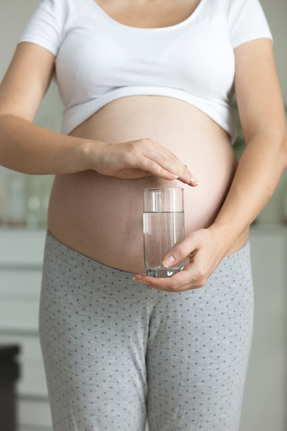 Closeup zwangere vrouw poseren met glas water