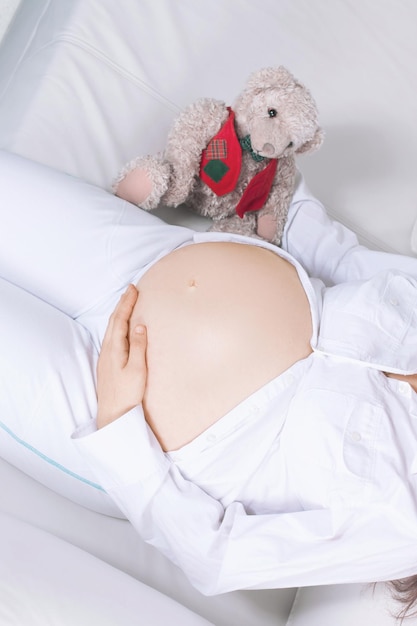 Closeupbeautiful pregnant woman with a soft toy lying on the couch