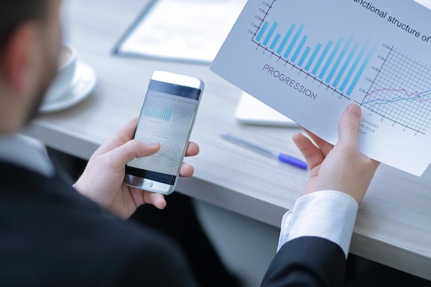 Closeupbusinessman checks the financial data using a smartphone