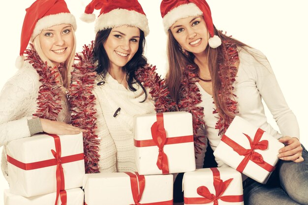 Closeupthree young women in hats of Santa Claus with Christmas gifts