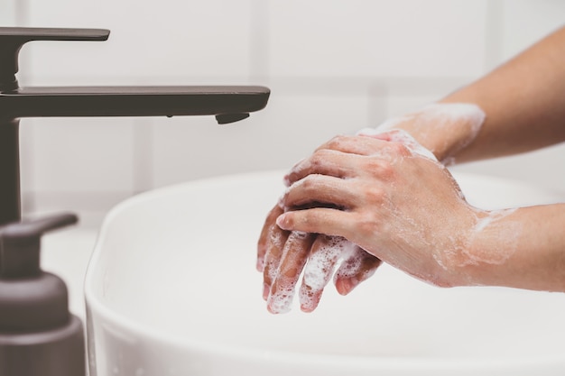 Фото Крупным планом азиатская женщина мыть руки водой из крана в ванной комнате дома здравоохранение covid19