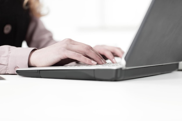 Крупным планоммолодая деловая женщина, работающая на ноутбуке