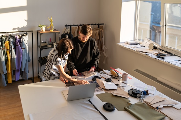 Clothes designers team choose material for sewing new collection dressmakers work in design studio