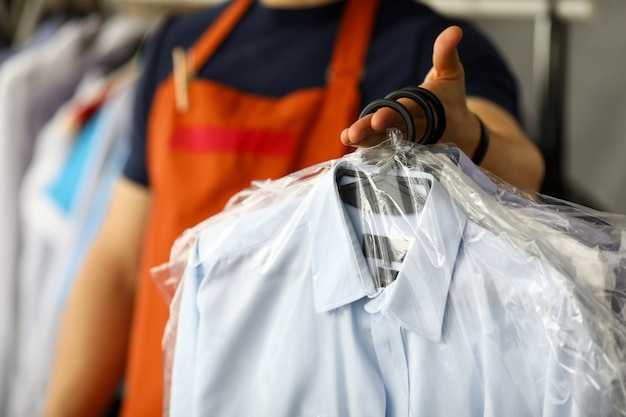 Photo clothes dry cleaning service worker returning shirts to customer