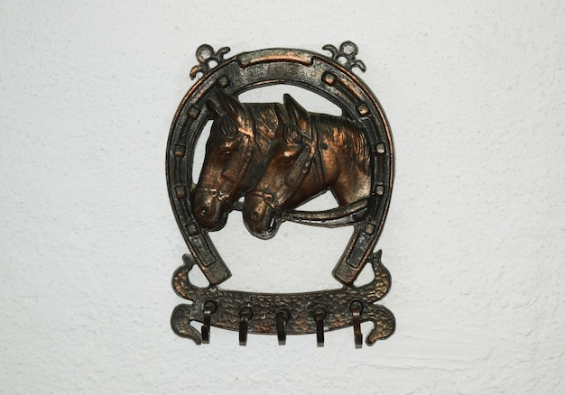 Clothes hanger decorated with the image of a horseshoe and the heads of horses