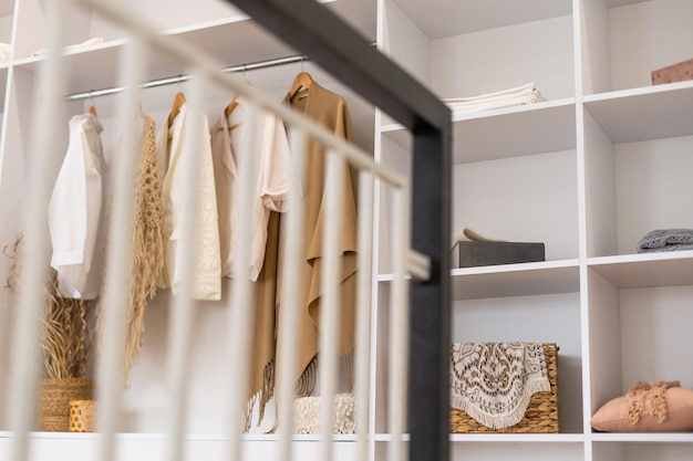 Фото Одежда висит на рельсах в белом шкафу с коробкой и обувью.