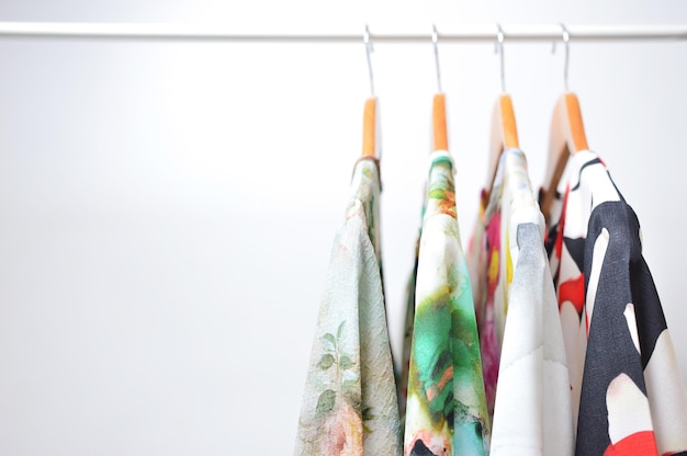 Clothes hanging on a rail in a white background.