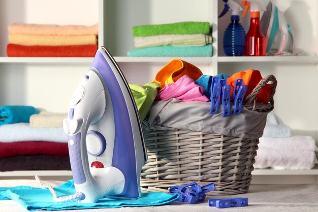 Clothes and iron on table on shelves background