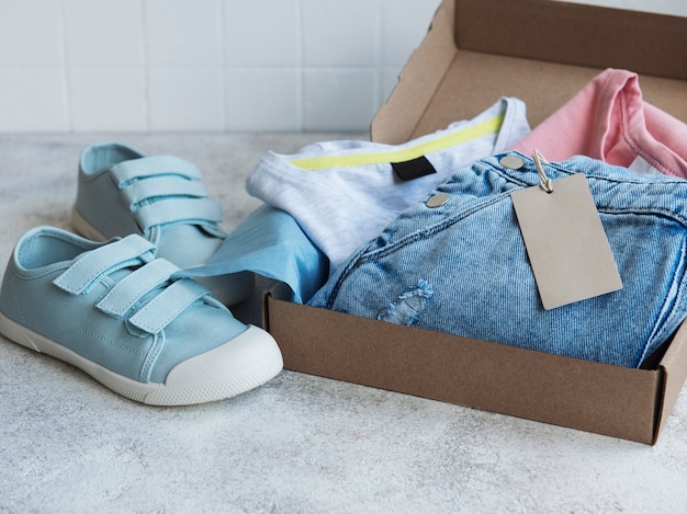 Clothes for kids in an open cardboard box. Online shopping concept