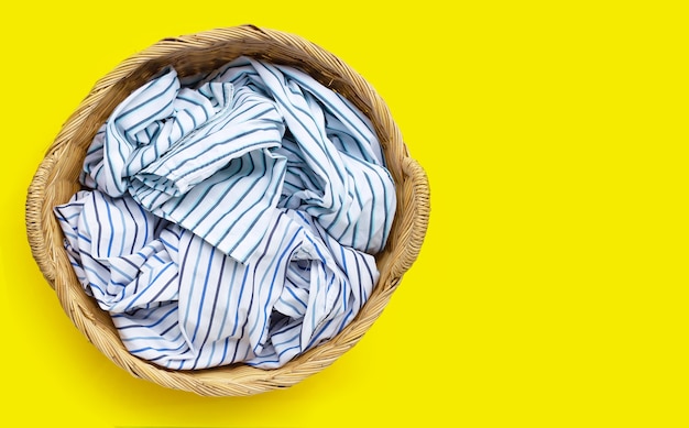 Clothes in laundry basket on yellow background. copy space