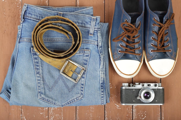 服の靴とアクセサリートップビューベルト半靴カメラと木製の背景にブルージーンズ