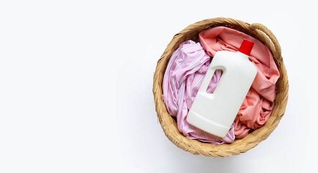 Clothes with plastic bottle of  detergent in laundry basket on white background. Copy space