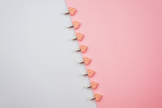 Clothespins with hearts on a white pink surface