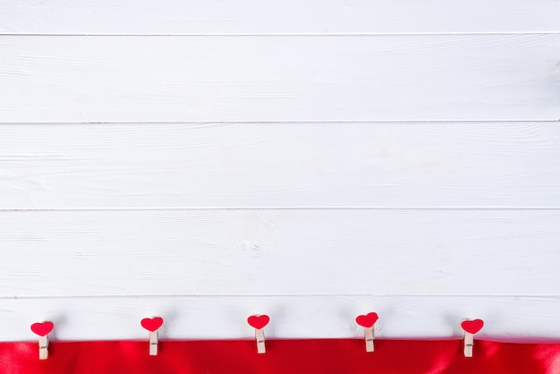 Photo clothespins with red hearts on a red ribbon on a white wooden background of valentine day