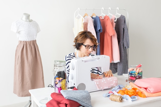 clothing designer, seamstress, people concept - clothing designer working in her studio